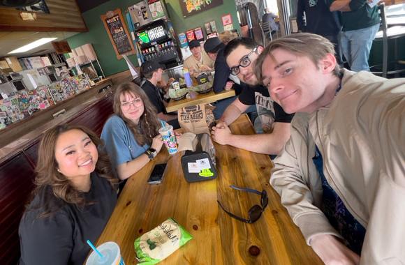 Selfie of four graduate students at table in restaurant.